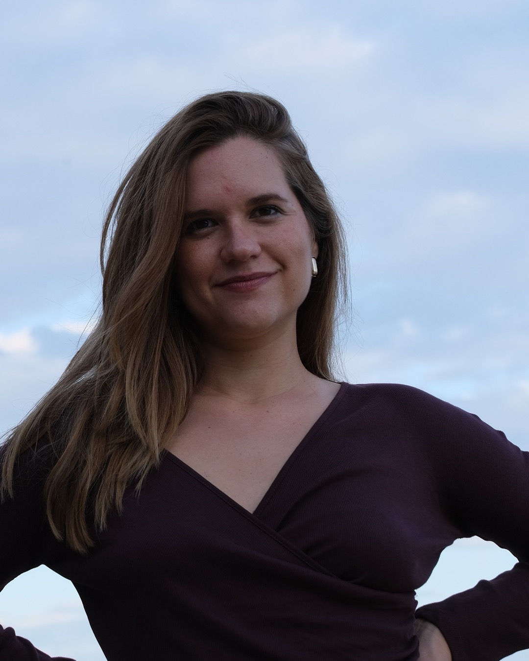 Portrait of Merce smiling against a soft blue evening sky