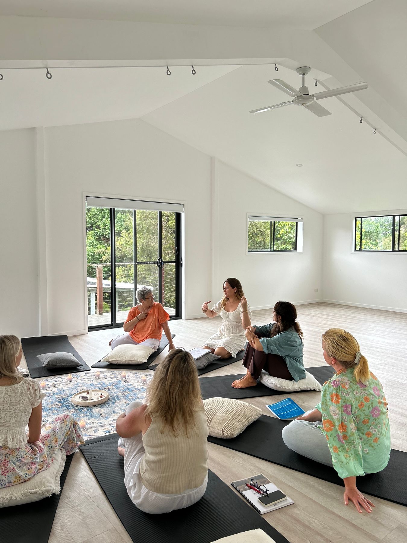 Merce talking with members of The Motion Room, seated together on mats in a bright room